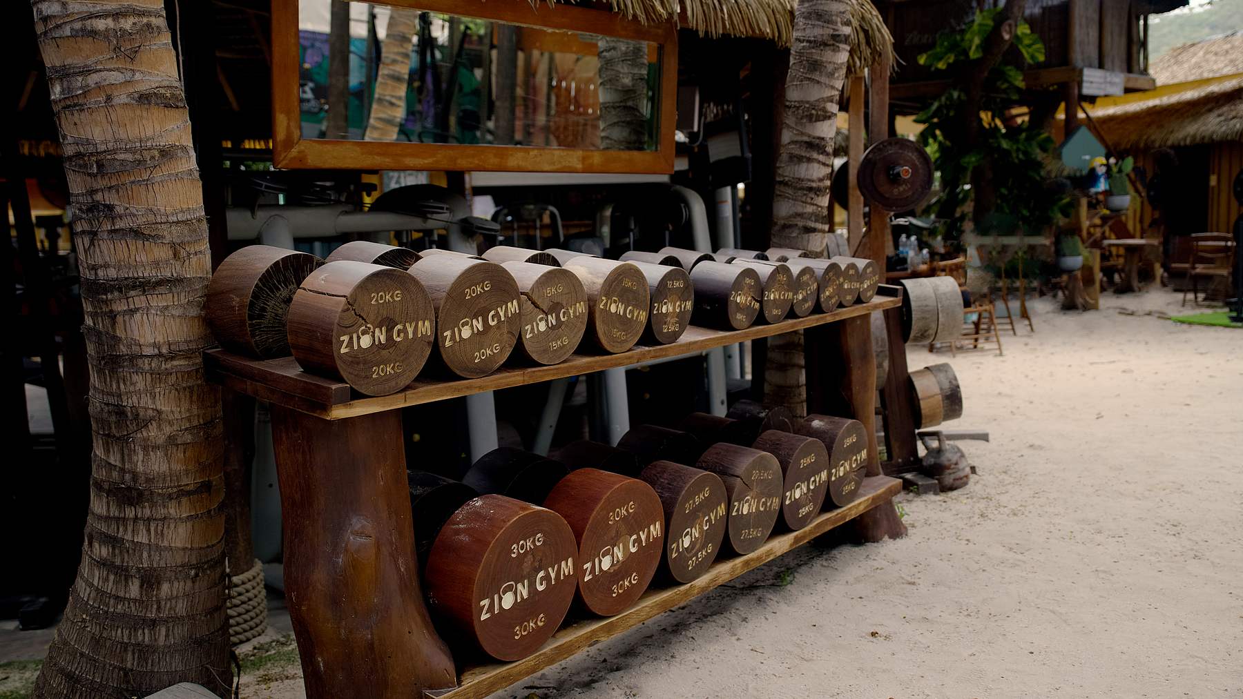 Le râtelier d'haltères en bois du Zion Gym, sous les cocotiers